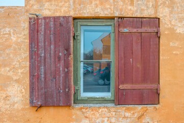 Obraz premium Old Rustic Window with Red Wooden Shutters on Orange Wall