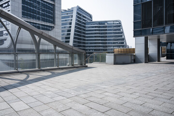 Fototapeta premium Modern urban architectural complex with pedestrian bridge and empty plaza under clear sky