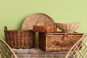 Wicker baskets on rattan table near green wall