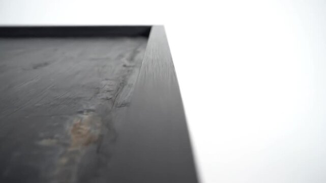 A slightly out-of-focus close-up of a dark, textured surface with hints of rust and a frame