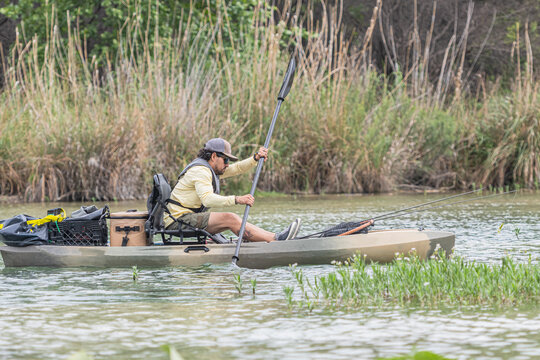 Man navigating kayak through green wetlands