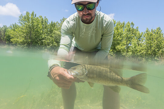 Split-Shot of Kayak Angler Landing a Smallmouth Bass in Clear Water