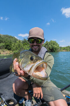 Angler Proudly Holding Large Largemouth Bass on Kayak
