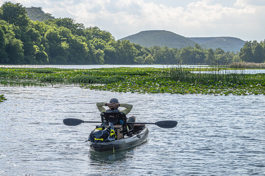 Kayak Fisherman Relaxing on Scenic Lake with Mountain Backdrop
