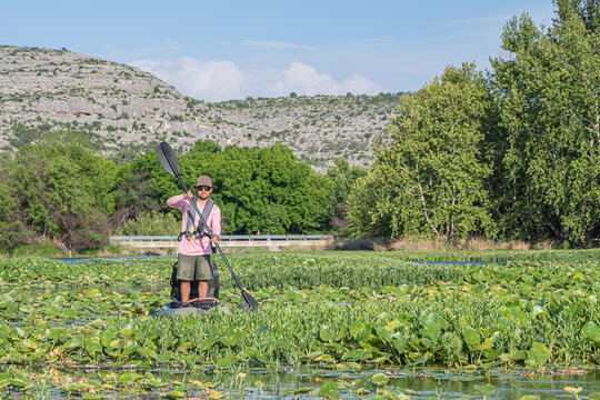 Kayak Angler Paddling Through Lily Pad Covered Lake