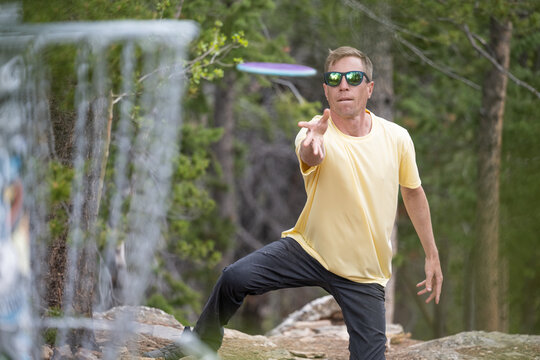 Focused Male Athlete Putting a Disc into basket