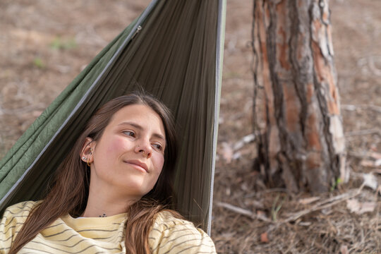 Young woman relaxing in hammock outdoors enjoying nature