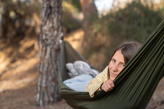 Happy young woman relaxing in forest hammock