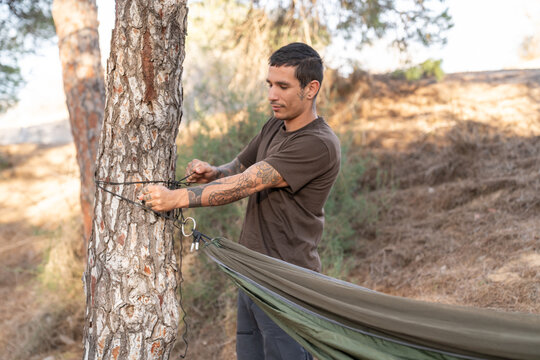 Man setting up hammock straps on tree trunk