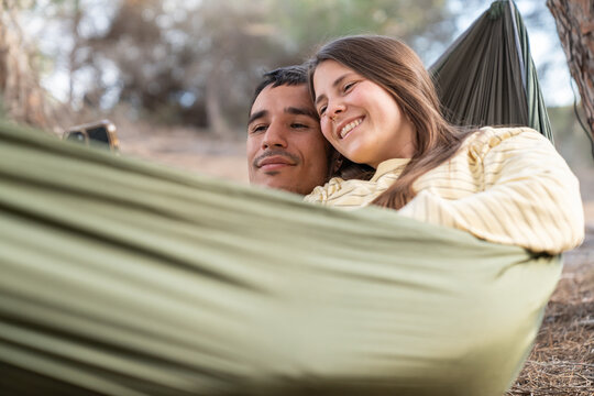 Happy couple viewing smartphone content in a hammock outdoors