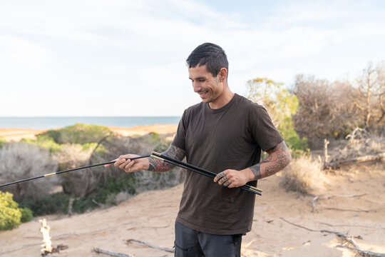 Happy man assembling tent poles for beach camping