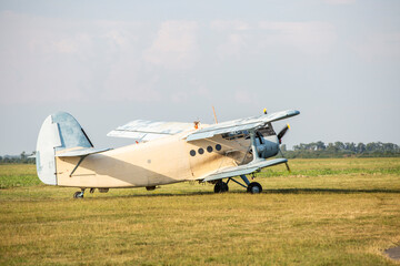 A classic biplane stands on a grass runway under a clear sky. © fotosr52