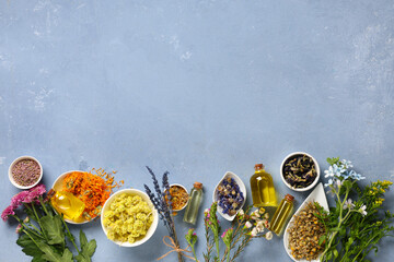 Bottles of essential oil with dried flowers on blue grunge background