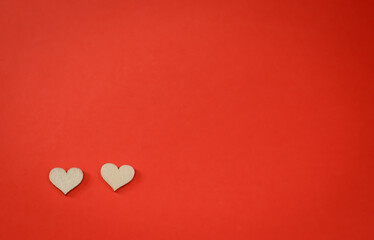 Red background with a pair of small wooden hearts with copyspace