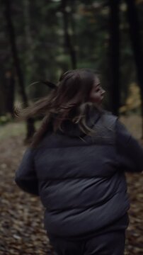Woman looking back while running in autumn forest