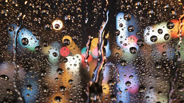 Raindrops on glass with blurred city lights reflecting through
