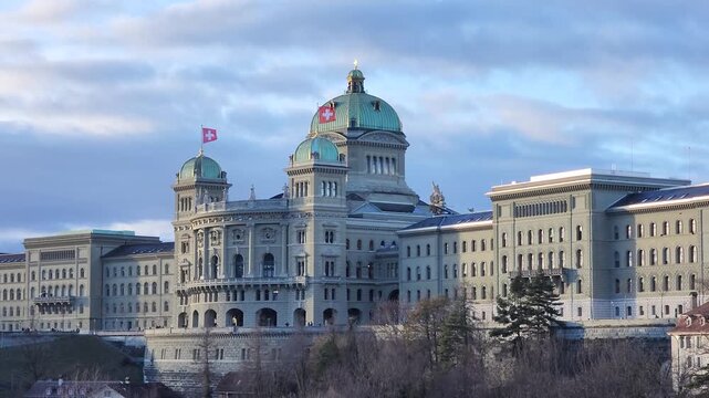 Horizontal view of the swiss parliament buildings with the swiss flag waving on the wind on February 11, 2026 in Bern, Switzerland.	