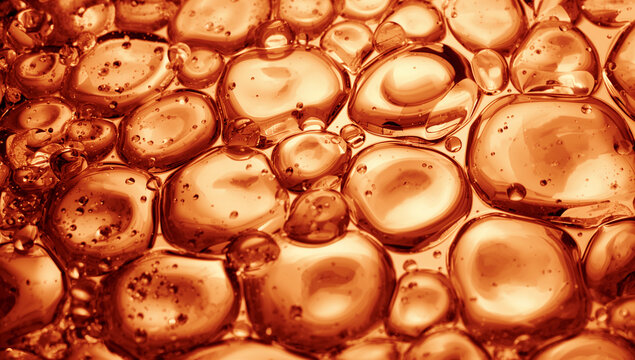 Close-up abstract view of amber-colored liquid bubbles and droplets forming a textured pattern