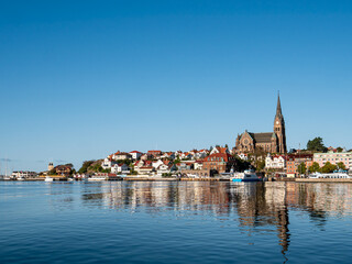 Obraz premium Lysekil town skyline with church and waterfront buildings reflected in calm water, seen from Gullmarn fjord, Bohuslän, west coast Sweden