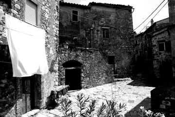 Naklejka premium Borghi toscani in bianco e nero. L'architettura medievale dei borghi toscani, caratterizzata da pietra, cotto, riflette il periodo comunale con cinte murarie, torri, vicoli stretti e piazze. Italia. 