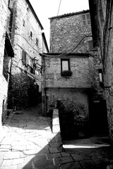 Naklejka premium Borghi toscani in bianco e nero. L'architettura medievale dei borghi toscani, caratterizzata da pietra, cotto, riflette il periodo comunale con cinte murarie, torri, vicoli stretti e piazze. Italia. 