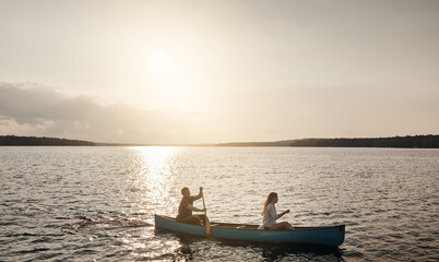 Couple, canoe and sunset on lake for hobby, vacation and outdoor weekend. Adventure, space and man with woman in boat for rowing, water activity and travel for bonding with summer holiday together
