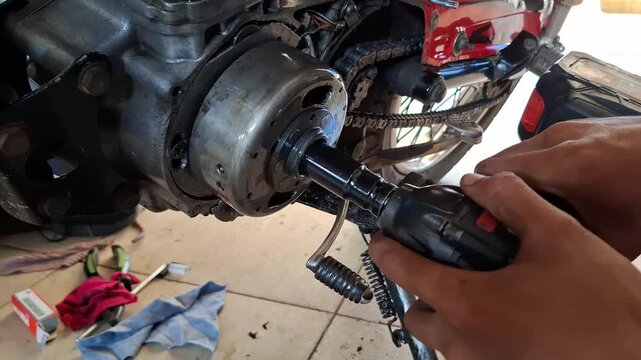 Close-up of a vocational student using an impact wrench to remove a motorcycle flywheel during mechanical workshop practice