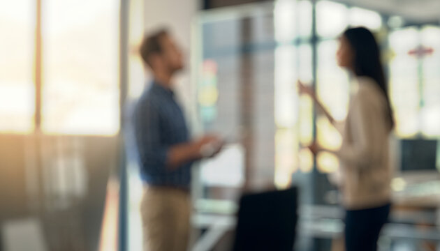 Two individuals appear to be engaged in a conversation within a modern office setting. The image is blurred, emphasizing their interaction more than specific details.