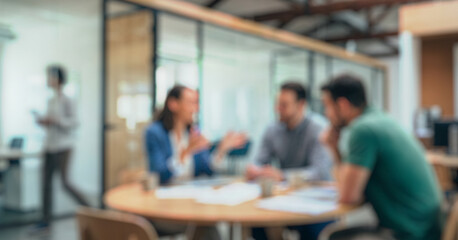 Blurred image of a group of professionals engaged in a meeting. Two individuals are discussing while a third person is working in the background, creating a collaborative