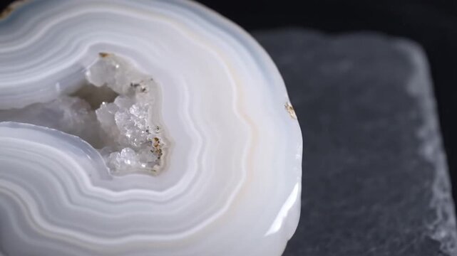 A close-up view of a geode with layered bands of white and pale gray, crystalline interior