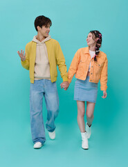 Young couple holding hands walking together in playful lifestyle moment expressing love freedom and joyful relationship connection in modern casual fashion.