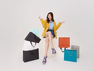 shopping decision concept with Asian woman sitting among shopping bags gesturing thoughtfully representing consumer choice spending strategy and modern lifestyle purchasing behavior.