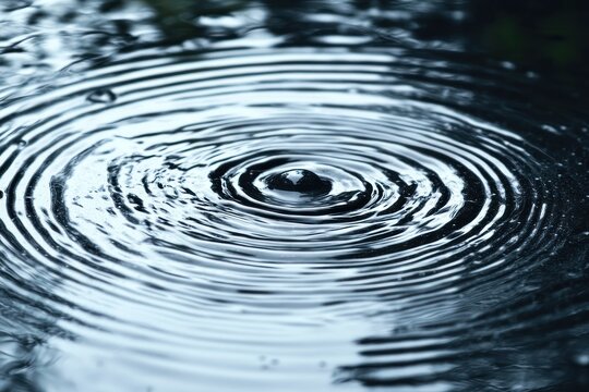 single water droplet forming concentric ripples on a dark reflective surface, serene and meditative mood