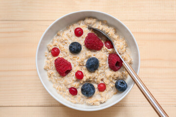 Bowl with tasty oatmeal and berries on wooden background, closeup