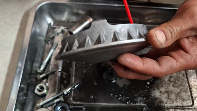 Close-up of vocational automotive student cleaning scooter CVT variator component with spray degreaser in workshop practice session