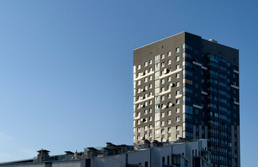 Modern apartment tower building in urban residential area. Gray facade with many windows rises © valiantsin