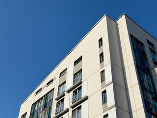Modern apartment building facade in urban residential area. White brick exterior with glass windows