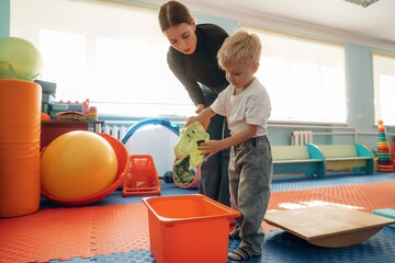 Doing balance training exercises. Preschool child with teacher during developmental activities in a playroom