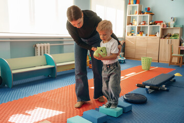 Path with cubes, balance training. Preschool child with teacher during developmental activities in a playroom
