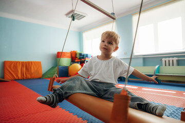 Swinging, sitting. Cute preschool child, boy, during developmental activities in a playroom
