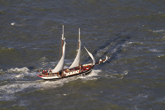 Hook of Holland, Netherlands - 11 February 2026: Aerial view of a majestic sailboat gracefully navigating the choppy, sun-kissed waters of the North Sea.