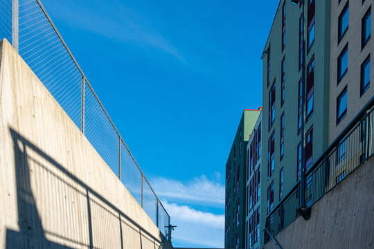 Street alley in modern urban architecture with strong perspective along building facade under blue sky leaving clean space for copy background