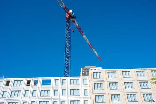 Daylight sky frames modern urban building facade as crane construction architecture rises with generous space for copy in clean exterior scene