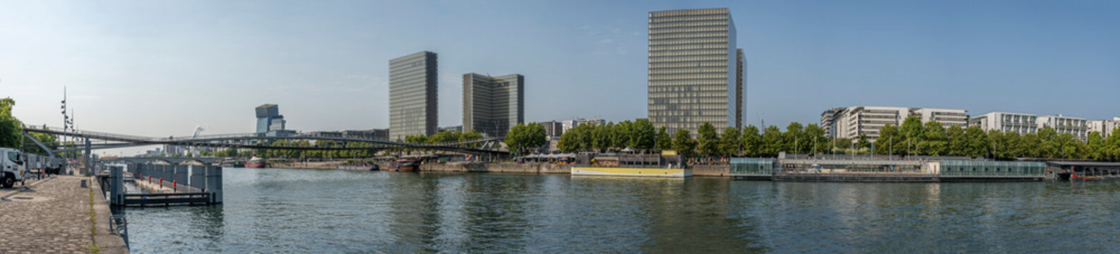 Paris, France - 08 15 2025: La Seine River. Panoramic view of the Simone de Beauvoir footbridge, the towers of the Fran&ccedil;ois-Mitterrand Library and the Summer swimming pool in Quay de Bercy