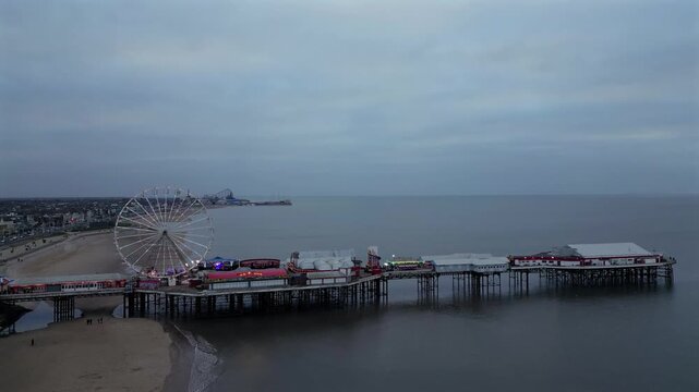 Breathtaking aerial view of Blackpool pier with Ferris wheel and rides above the ocean on a cloudy day