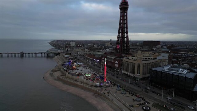 Captivating aerial view of Blackpool Tower and festive seaside amusement park under a moody sky