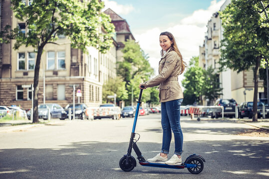 Portrait of smiling woman with E-Scooter in the city