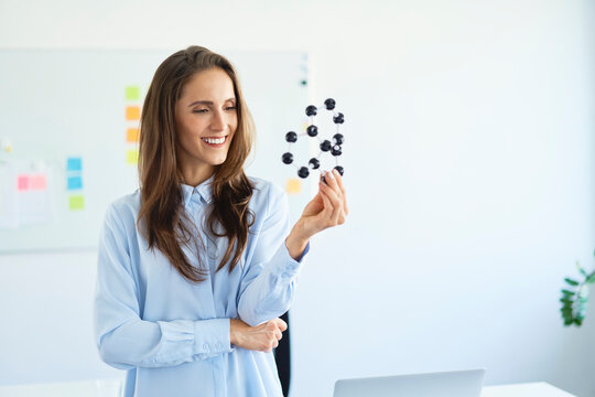 Smiling young scientist looking at graphene model in office