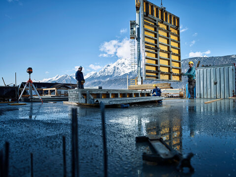 Construction workers lifting pywood with crane