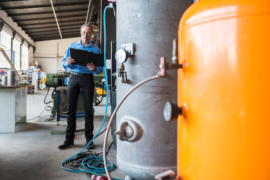 Man with clipboard on factory shop floor